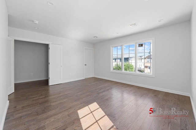 unfurnished room with baseboards and dark wood-style flooring