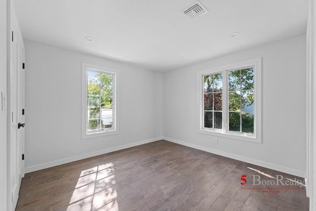 unfurnished room with baseboards, wood finished floors, and visible vents