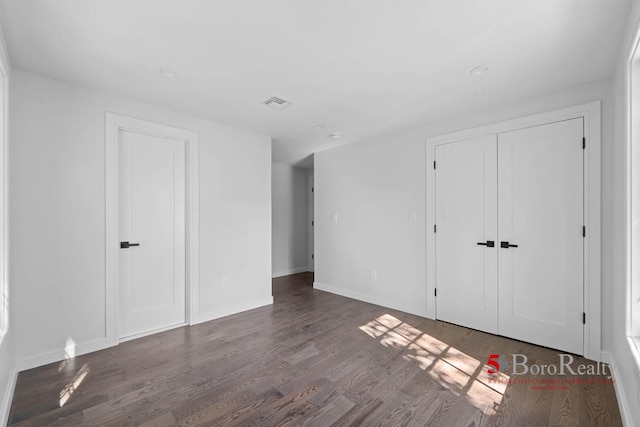 unfurnished bedroom featuring baseboards, visible vents, wood finished floors, and a closet