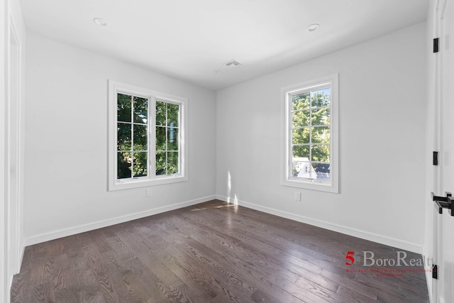 spare room with baseboards and dark wood-type flooring