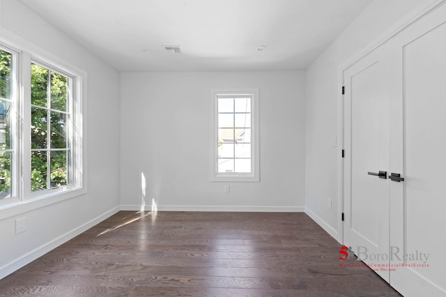 unfurnished room featuring visible vents, baseboards, wood finished floors, and a healthy amount of sunlight