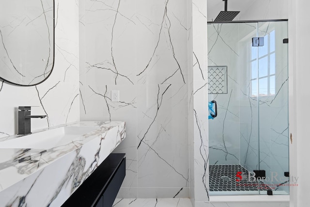 bathroom featuring tile walls, a marble finish shower, and vanity