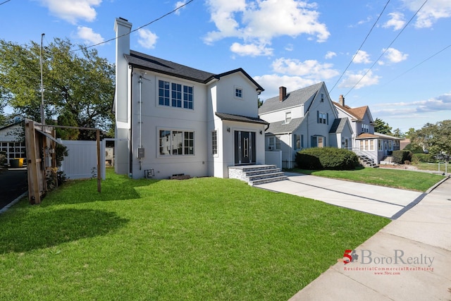 view of front of home with a standing seam roof, a chimney, fence, a front lawn, and stucco siding