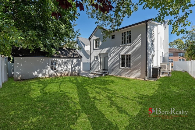 back of property featuring a fenced backyard, a yard, a chimney, and entry steps