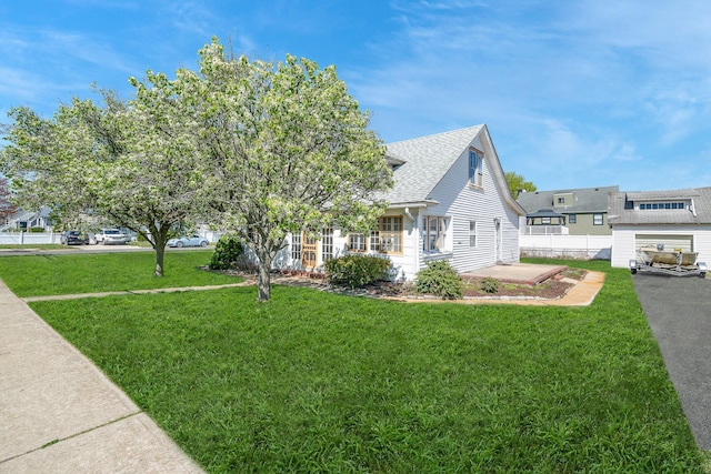 view of side of home featuring a yard, a patio, fence, and roof with shingles
