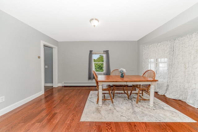 dining space featuring baseboards, wood finished floors, and a baseboard radiator