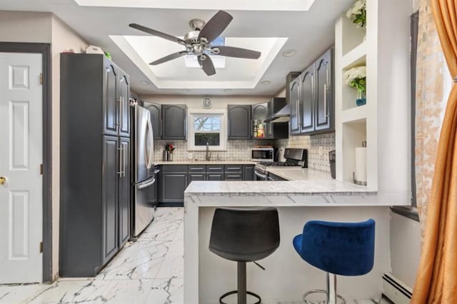 51 Graham St, Farmingdale, NY 11735 - kitchen featuring a peninsula, a breakfast bar area, backsplash, a skylight, and stainless steel appliances