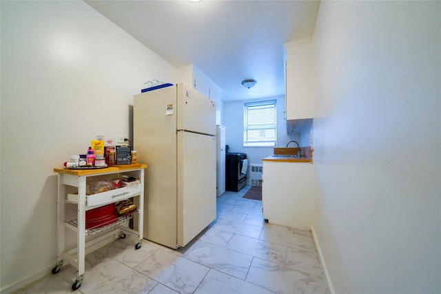 1480 Thieriot Ave Unit 2C, Bronx, NY 10460 - kitchen featuring freestanding refrigerator, light marble finish floors, a sink, white cabinets, and baseboards