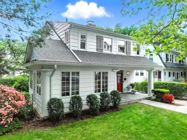 view of front of home with a chimney, a front yard, and a shingled roof