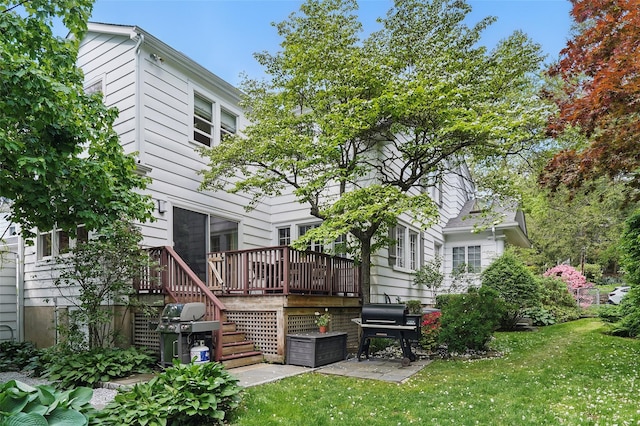 back of house with a wooden deck, a lawn, and stairs