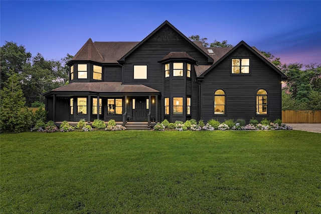 view of front facade with roof with shingles, fence, a porch, and a front yard