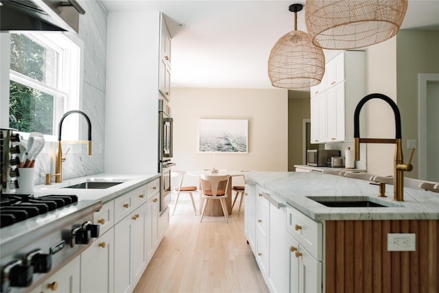 kitchen with light wood-style floors, a sink, backsplash, and stainless steel appliances