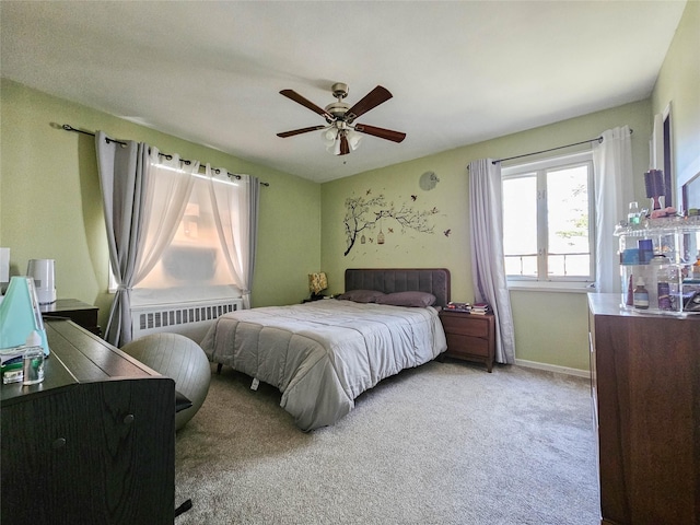 carpeted bedroom featuring radiator heating unit, baseboards, and a ceiling fan