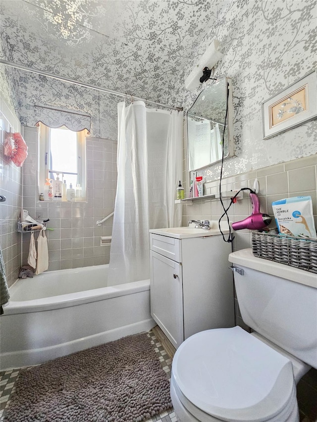 bathroom with vanity, toilet, shower / bath combo with shower curtain, wallpapered walls, and tile walls