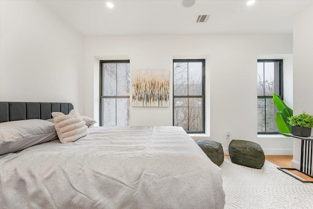 bedroom featuring visible vents, baseboards, wood finished floors, and multiple windows