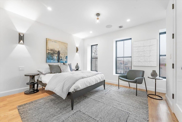 bedroom with baseboards, recessed lighting, wood finished floors, and visible vents
