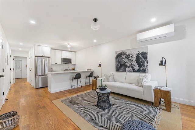 living area with light wood-style floors, baseboards, an AC wall unit, and recessed lighting