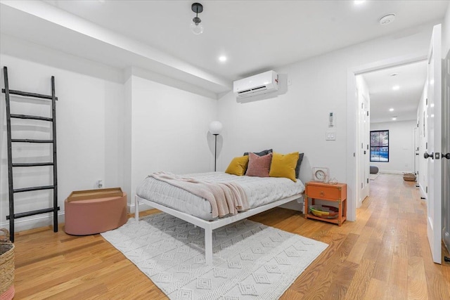 bedroom with light wood-type flooring, a wall mounted air conditioner, and recessed lighting