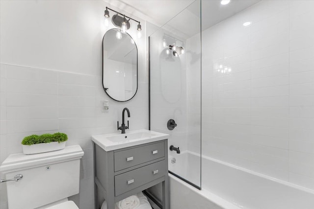 bathroom with vanity, toilet, tile walls, and tub / shower combination