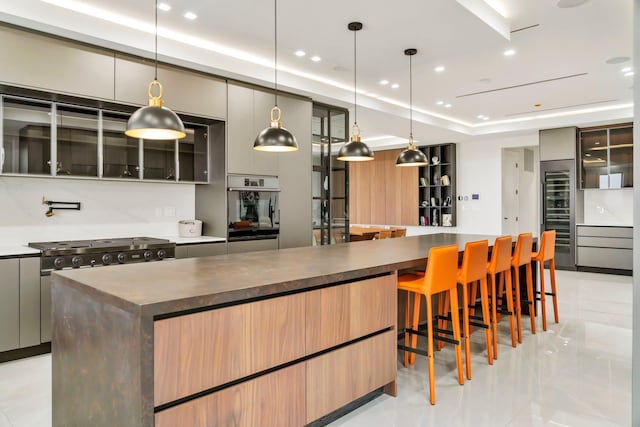 kitchen with a tray ceiling, dark countertops, gray cabinets, and stainless steel oven