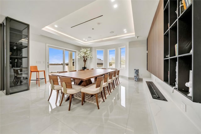 dining space featuring baseboards, a raised ceiling, light tile patterned floors, and a wealth of natural light