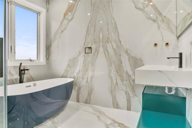 full bath with a freestanding bath, tile walls, and a sink