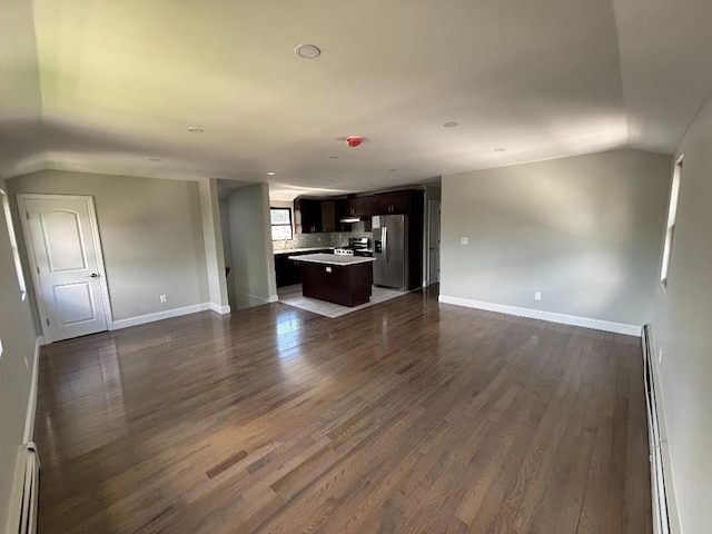 177-37 115th Ave, Saint Albans, NY 11434 - unfurnished living room featuring baseboard heating, vaulted ceiling, dark wood-style flooring, and baseboards