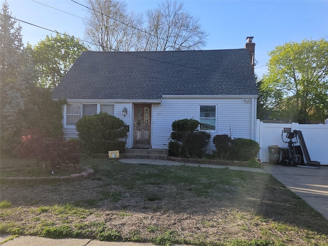new england style home featuring fence, a chimney, and a shingled roof