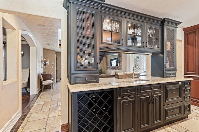 84 S Woods Rd, Woodbury, NY 11797 - bar featuring stone tile floors, a textured ceiling, baseboards, a sink, and arched walkways
