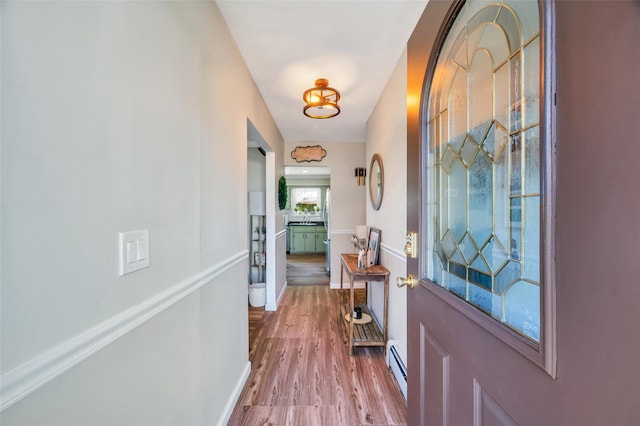 entryway with baseboards, wood finished floors, and a baseboard radiator