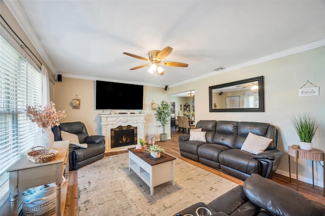living room featuring baseboards, ornamental molding, light wood-style flooring, and a ceiling fan