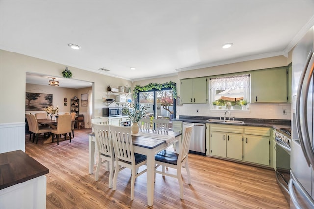 kitchen featuring backsplash, dark countertops, a sink, green cabinets, and stainless steel appliances
