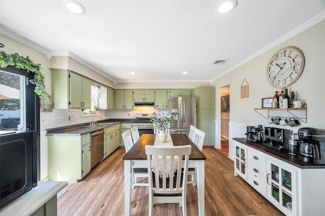 kitchen with a sink, green cabinetry, dark countertops, and stainless steel appliances