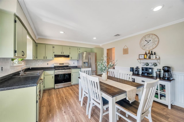 kitchen featuring ornamental molding, dark countertops, under cabinet range hood, green cabinets, and stainless steel appliances