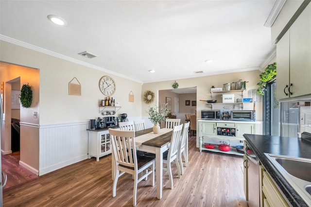 dining room featuring visible vents, ornamental molding, and light wood finished floors
