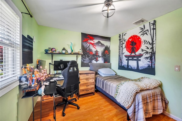 bedroom with visible vents, wood finished floors, and multiple windows