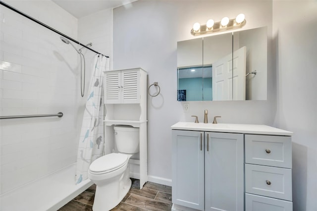 bathroom featuring vanity, wood finished floors, a tile shower, and toilet