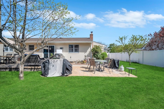back of property featuring a fenced backyard, a patio, a chimney, and a lawn
