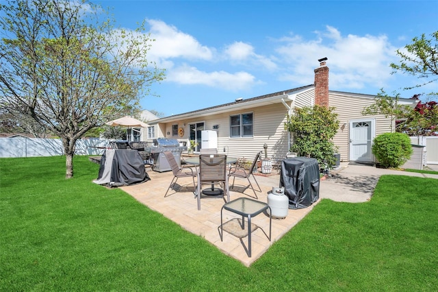 back of property featuring a yard, fence, a chimney, and a patio area