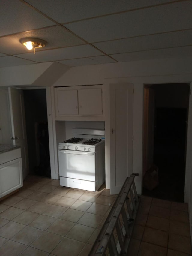 kitchen with light countertops, light tile patterned flooring, white range with gas cooktop, and white cabinetry