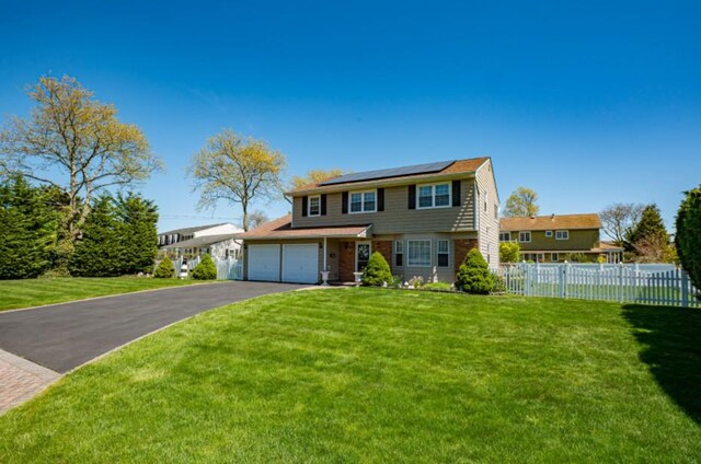 20 Bayview Rd, Amityville, NY 11701 - traditional-style house with a front lawn, roof mounted solar panels, driveway, and fence