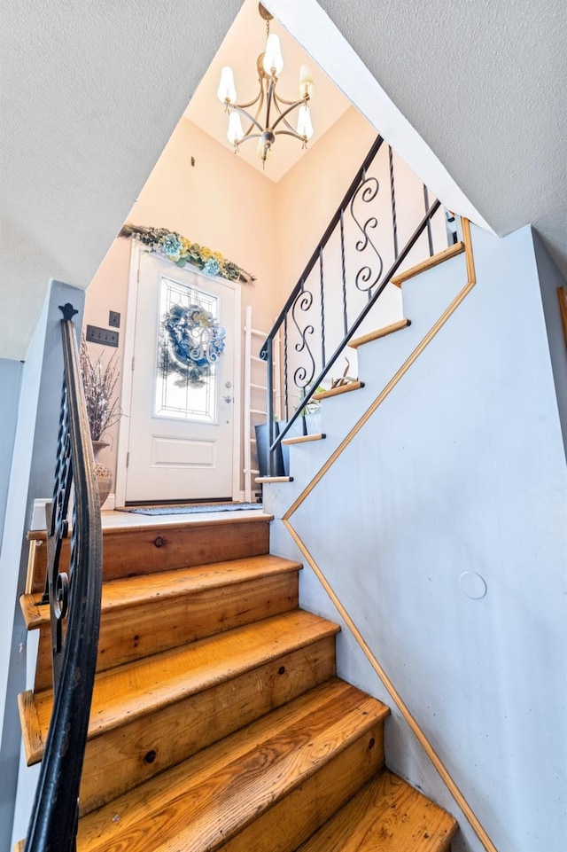staircase with a textured ceiling and a chandelier