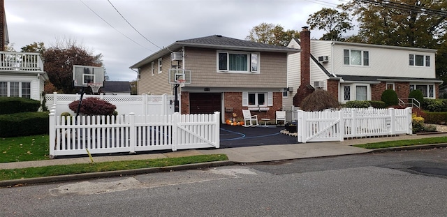 view of front facade featuring a chimney, a gate, brick siding, aphalt driveway, and an attached garage