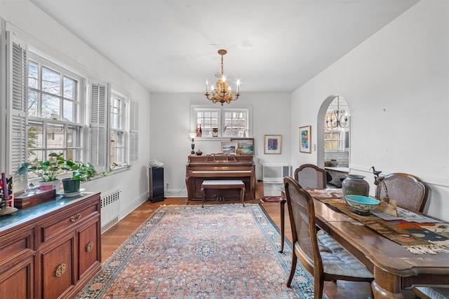 50 Oakland Ave, Tuckahoe, NY 10707 - dining area with a notable chandelier, baseboards, radiator heating unit, wood finished floors, and arched walkways