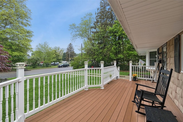 wooden terrace featuring a lawn, covered porch, and view of scattered trees