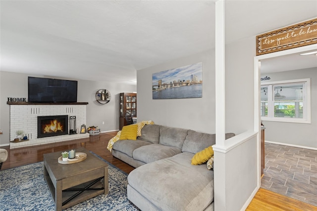 living area with a brick fireplace, baseboards, and stone finish floors