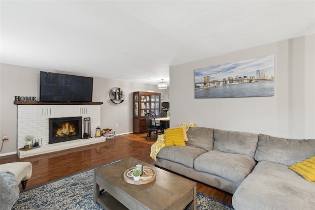 living area featuring wood finished floors, a fireplace, baseboards, and a chandelier