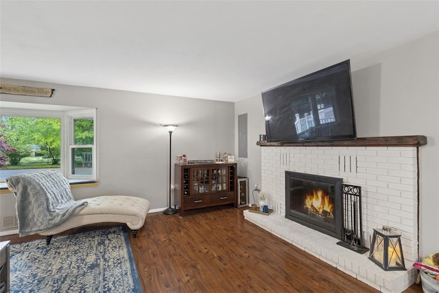 living area with wood finished floors, a brick fireplace, and baseboards