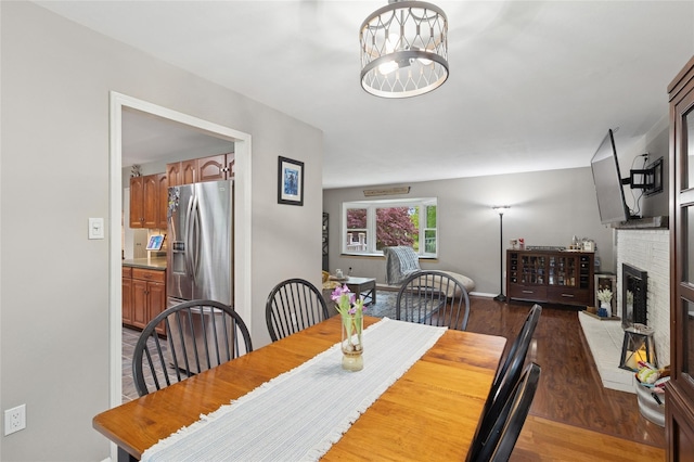 dining area featuring wood finished floors, a fireplace, baseboards, and a chandelier