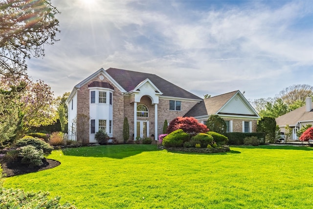view of front facade featuring brick siding and a front yard
